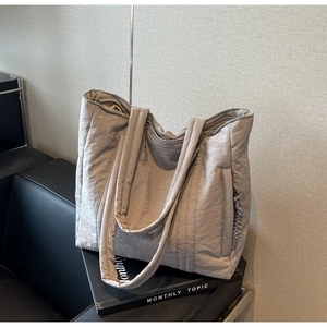 Close-up detail of light purple nylon tote bag showing zipper pocket and fabric texture
