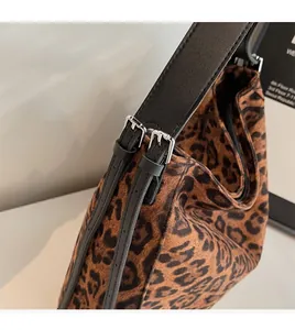 Detail of adjustable leather strap with silver metal buckle on leopard print tote bag