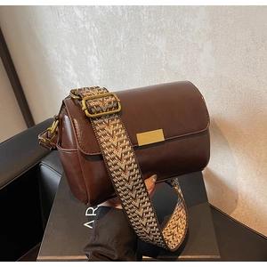 Detail of vintage brown leather bag featuring golden buckle and ethnic wide strap