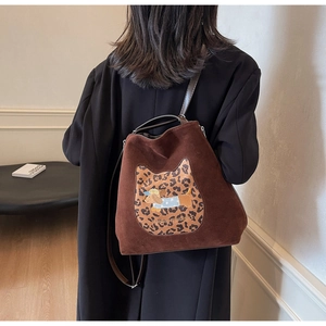 Brown suede tote bag with leopard cat patch and puppy embroidery shown on model's shoulder