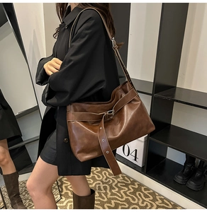 Close-up of soft dark brown leather tote bag with decorative metal buckle strap