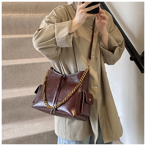 Dettaglio macro della borsa in pelle marrone scuro lucido con catena d'oro e tasche