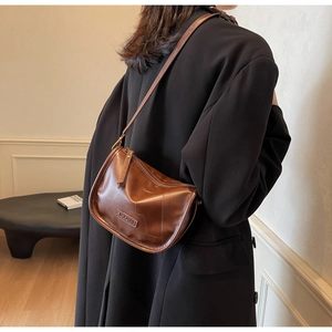 Détail d'un sac à bandoulière en cuir marron vintage avec logo embossé au dos