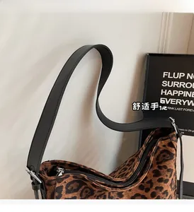 Detail of leopard print shoulder bag featuring a wide black strap and silver metal buckle