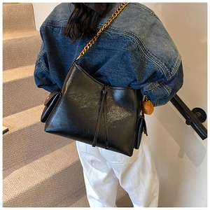 Dettaglio borsa tote in ecopelle nera con tracolla a catena dorata e nappa decor