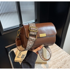 Detail of vintage brown leather pillow bag with wide geometric woven shoulder strap