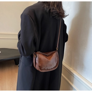 Détail du sac besace vintage marron avec logo embossé et détails en métal doré