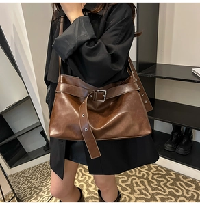 Detail of a deep brown vintage faux leather tote bag with metal buckle and strap design