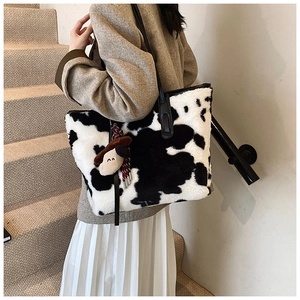 Close-up of fluffy cow print tote bag detail with soft plush texture and cartoon pendant