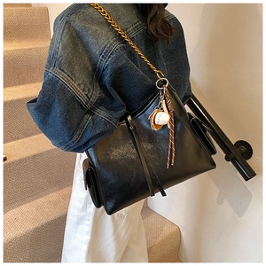 Dettaglio borsa tote in pelle nera con catena dorata e ciondolo da baseball