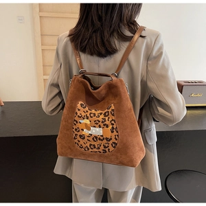 Detail of a brown suede bag with leopard cat patch and dog embroidery on model back