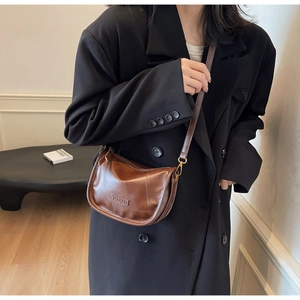 Détail d'un sac demi-lune marron vintage porté avec un blazer noir sur un mannequin