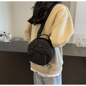 Petit sac rond en nylon pour femme porté à l'épaule, vue latérale élégante