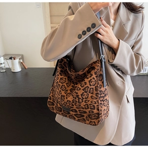 Detail of a leopard print tote bag with adjustable leather strap on a fashion model