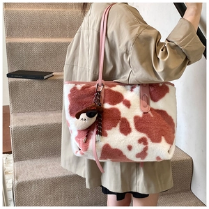 Detail of pink cow print plush tote bag with leather strap and cute dog charm accessory