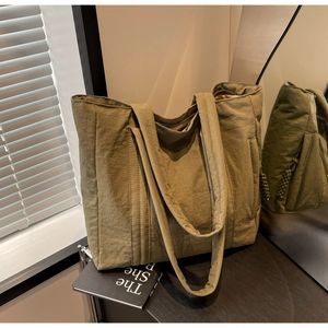 Detail view of large olive green tote bag featuring double handles and durable zip closure