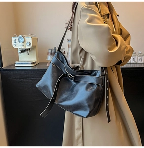 Detail of a vintage black PU leather shoulder bag featuring metal eyelets and buckle strap