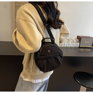 Détail du sac bandoulière en nylon noir avec sangle ajustable et logo métallique