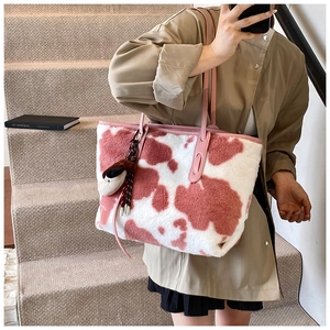 Detail of pink cow print plush tote bag with furry texture and thin leather strap