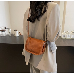 Détail d'un sac bandoulière vintage marron porté avec un blazer gris clair élégant