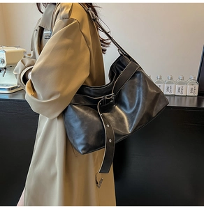 Detailed view of a black leather hobo bag with adjustable strap and silver metal buckle