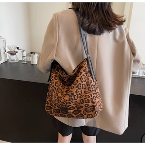 Detail of leopard print tote bag with adjustable black strap and logo patch on front