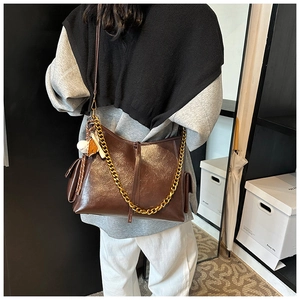Dettaglio della borsa hobo marrone in vernice con catena dorata e ciondolo morbido
