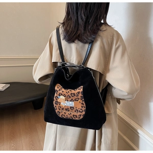 Detail of a black textured backpack with a leopard cat-ear pocket and embroidery