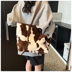 Detailed side view of large faux fur cow print tote bag with brown leather handles