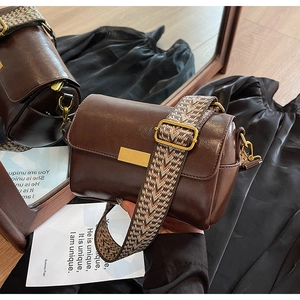 Detailed close-up of retro dark brown crossbody bag with wide geometric woven strap