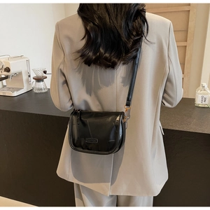 Sac à bandoulière noir avec coutures géométriques porté par un mannequin en costume