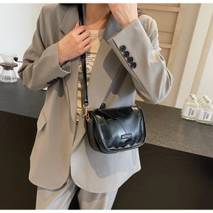 Détail d'un sac bandoulière en cuir noir avec design patchwork et boucles dorées