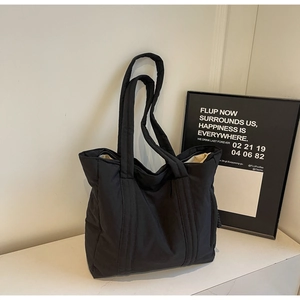 Close-up of a black quilted tote bag with a soft puffy texture and minimalist design