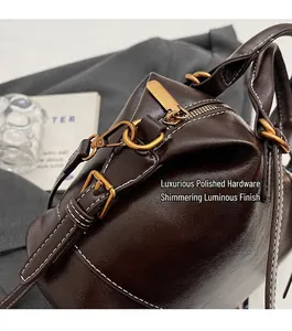 Dettaglio della borsa in pelle marrone vintage con fibbie dorate e cuciture bianche