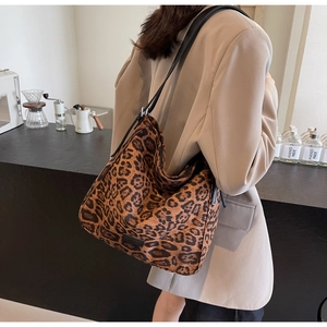 Chic leopard print hobo bag with black leather strap shown in a modern cafe setting