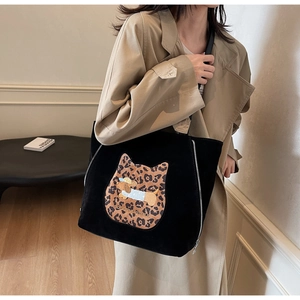 Detail of black suede tote bag featuring leopard cat patch and side silver zipper decoration