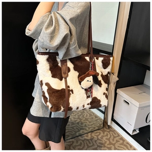 Detailed cow print plush tote bag featuring soft faux fur and brown leather straps
