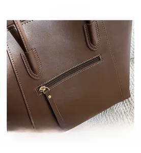 Detail view of large brown leather tote bag showing back zipper pocket and golden hardware