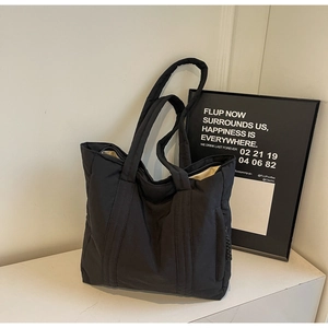 Close-up of black quilted tote bag with side hidden zipper pocket and neutral interior lining