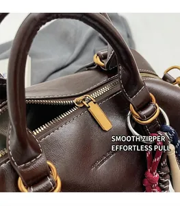 Dettaglio della borsa vintage in pelle marrone con trama litchi e zip dorata lucida