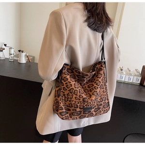 Fashionable leopard print tote bag with black leather strap worn in a cafe setting