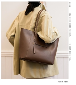 Detail of dark brown leather tote bag with rear zipper pocket shown on a beige coat