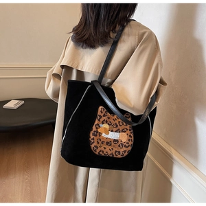Detailed view of black tote bag with embroidered leopard cat patch and puppy graphic
