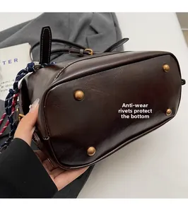 Vista dettagliata della base della borsa in pelle marrone con quattro rivetti protettivi vintage