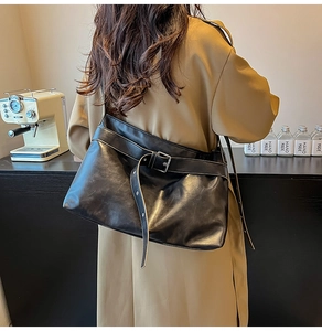 Detail of vintage black leather tote bag with stylish metal buckle and strap on model