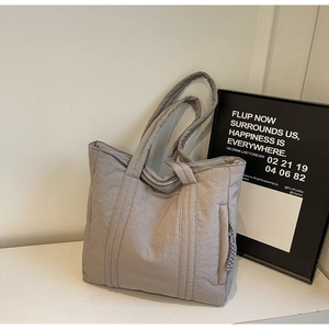 Macro detail of a gray quilted tote bag featuring a textured finish and side zipper pocket