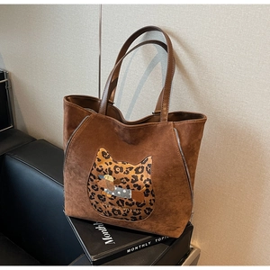 Detail of brown suede tote bag with leopard cat print and embroidered dog patch