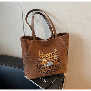 Detailed view of brown suede tote bag featuring a cute cat and puppy cartoon patch