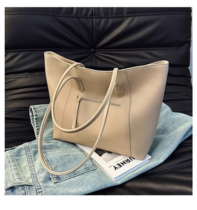 Detail of minimalist beige tote bag with metallic zipper and leather texture on a sofa