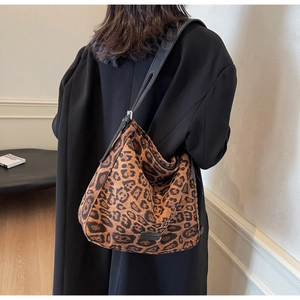 Detail of hobo leopard print tote bag with black strap worn over a black winter coat